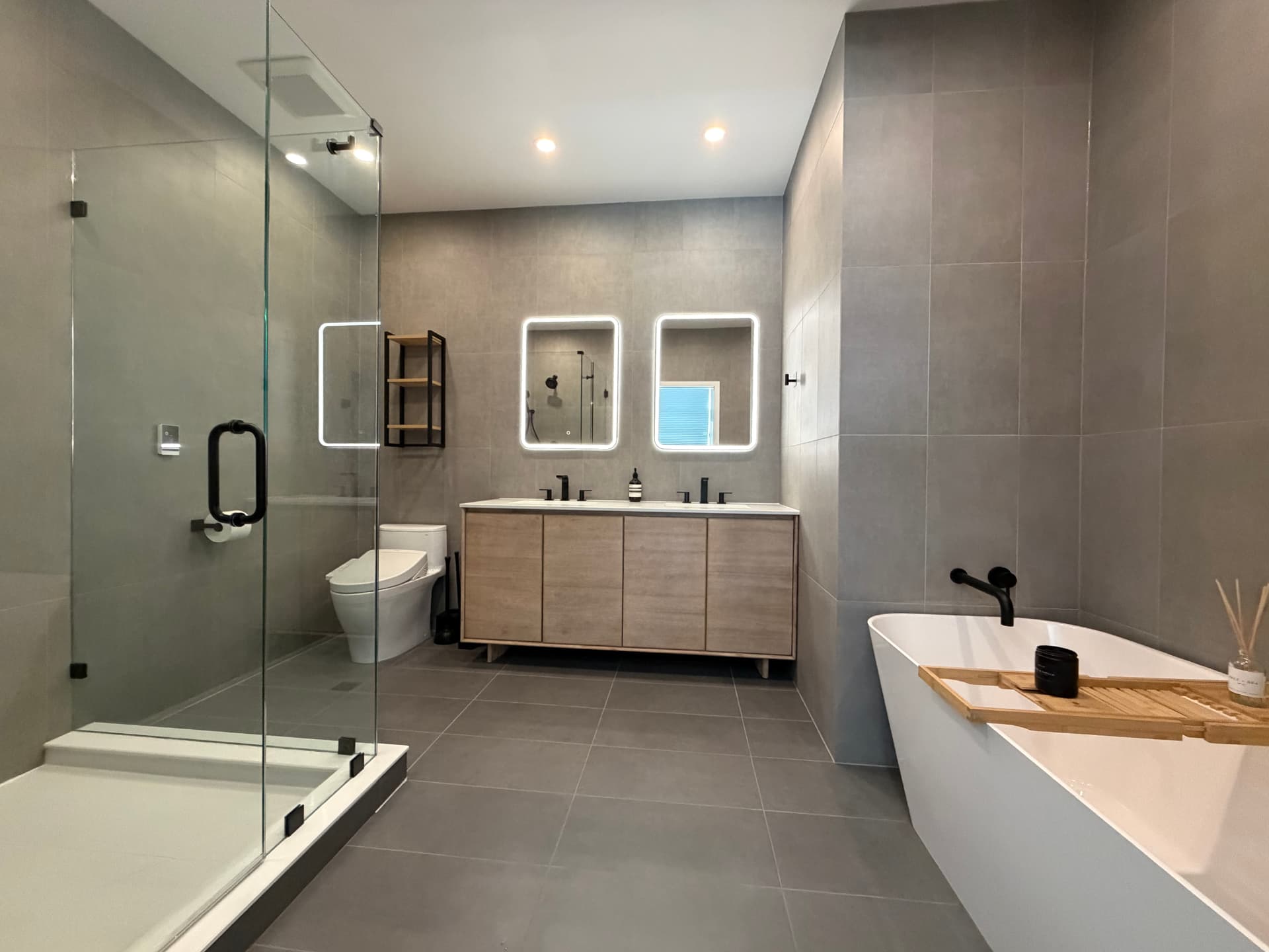 Remodeled bathroom with backlit LED mirrors and large-format tile